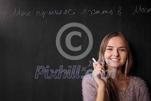 Pretty, young female student in front of a blackboard during class Pretty, young female student in front of a blackboard during class