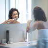 Pretty, middle aged woman brushing her teeth with braces in a modern design bathroom