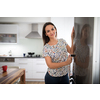 Pretty, young woman in her modern kitchen, by the fridge, about to cook a healthy meel for her family (color toned image)