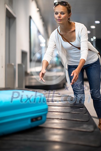 Young woman with her luggage at an international airport, waiting for her luggage to arrive at the baggage claim zone Young woman with her luggage at an international airport, waiting for her luggage to arrive at the baggage claim zone