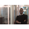  African American man looking at camera standing in office lobby hall. Multicultural company managers team portrait. High-quality photo