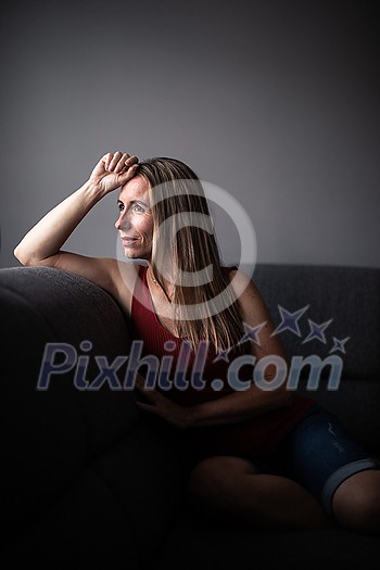 Mid-aged woman at home relaxing on a sofa (color toned image) Mid-aged woman at home relaxing on a sofa (color toned image)
