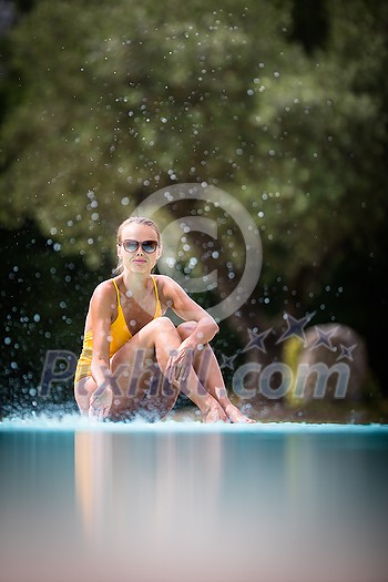 Young Beautiful Suntanned Woman wearing sunglasses relaxing next to a Swimming Pool on a lovely Summer Day Young Beautiful Suntanned Woman wearing sunglasses relaxing next to a Swimming Pool on a lovely Summer Day