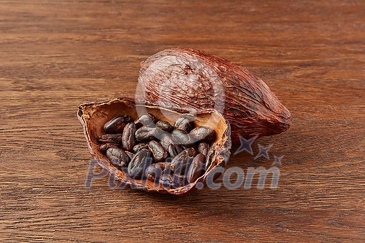 Organic natural pod of cocoa tree filled with brown cocoa beans placed on wooden background Organic natural pod of cocoa tree filled with brown cocoa beans placed on wooden background