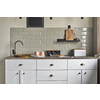 Elegant kitchen with old fashion copper sink and modern faucet, grayish tiles wall, cabinets, tea and coffee containers, pink cups, and magazin on wooden counter. Country house kitchen concept.