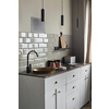 Modern creative idea of small kitchen with gray tiles wall with old fashion copper sink and modern faucet, tea and coffee containers, pink cups, and magazine on wooden counter.