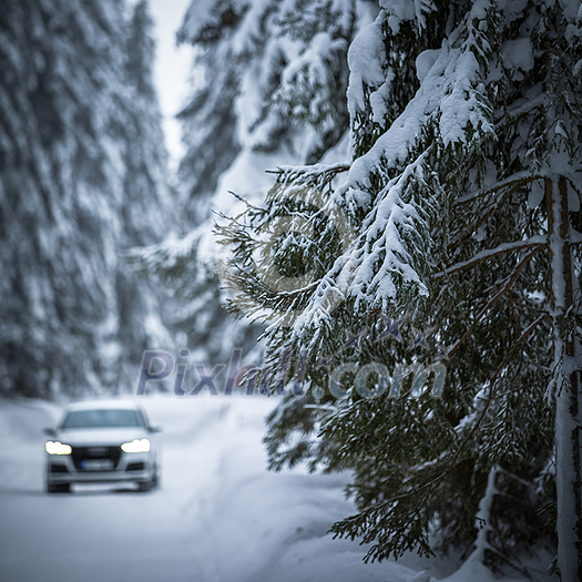 Car on a snowy winter road amid forests - using its four wheel drive capacities to get through the snow Car on a snowy winter road amid forests - using its four wheel drive capacities to get through the snow