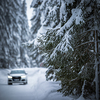 Car on a snowy winter road amid forests - using its four wheel drive capacities to get through the snow