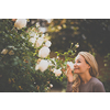 Lifestyle portrait of a young, pretty woman smelling some lovely roses in a garden