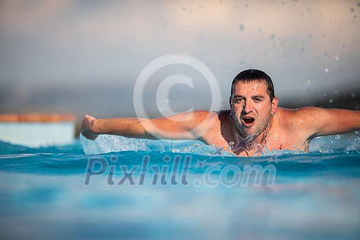 Male swimmer swimming in an outdoor pool - keeping fit