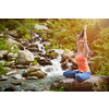 Woman in Hatha yoga asana Padmasana outdoors at tropical waterfall