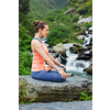 Woman in Hatha yoga asana Padmasana outdoors at tropical waterfall