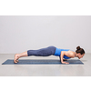 Woman doing Ashtanga Vinyasa yoga Surya Namaskar Sun Salutation asana Chaturanga Dandasana - four-limbed staff pose on yoga mat in studio on grey bagckground