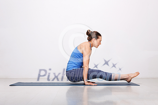 Woman doing Hatha asana Utpluti dandasana - lifted stuff pose on yoga mat on yoga mat in studio on grey bagckground Woman doing Hatha asana Utpluti dandasana - lifted stuff pose on yoga mat on yoga mat in studio on grey bagckground