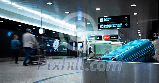 Arrived luggage going around on a conveyor belt waiting to be claimed at the baggage claim zone at a modern international airport