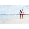 Romantic young couple on the beach waloking along the shore
