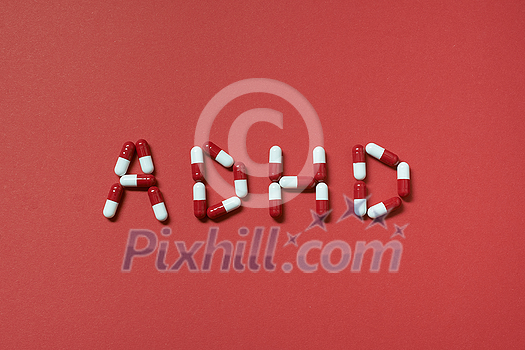 ADHD abbreviation formed of pharmaceutical pills on red background. Attention deficit hyperactivity disorder and mental health awareness. ADHD abbreviation formed of pharmaceutical pills on red background. Attention deficit hyperactivity disorder and mental health awareness.