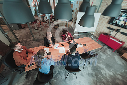Top view of young multi-ethnic business people working and communicating together in creative office. Selective focus. High-quality photo Top view of young multi-ethnic business people working and communicating together in creative office. Selective focus. High-quality photo