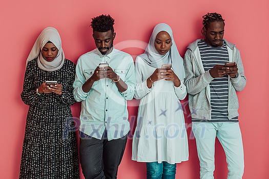A group of African Muslim students using smartphones while standing in front of a pink background. High-quality photo A group of African Muslim students using smartphones while standing in front of a pink background. High-quality photo