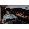 The young man on an urban city street at night texting on a smartphone with bokeh and neon city lights in the background. High-quality photo. High-quality photo