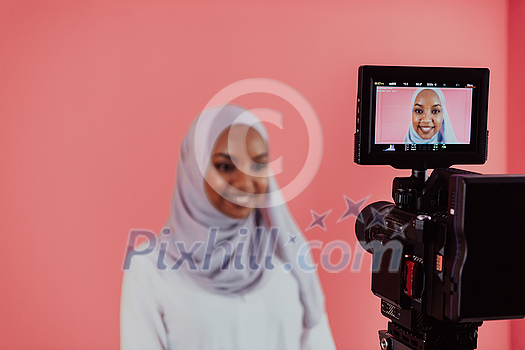 Videographer in digital studio recording video on professional camera by shooting female Muslim woman wearing hijab scarf plastic pink background. High-quality photo Videographer in digital studio recording video on professional camera by shooting female Muslim woman wearing hijab scarf plastic pink background. High-quality photo