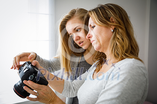 Mother and daughter taking photos and checking them on a modern digital DSLR camera Mother and daughter taking photos and checking them on a modern digital DSLR camera