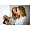 Mother and daughter taking photos and checking them on a modern digital DSLR camera