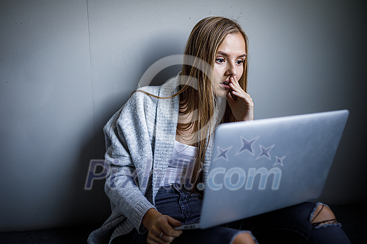 Pretty, young woman with her laptop studying for an exam/working