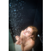 Pretty, young woman taking a long hot shower washing her hair in a modern design bathroom