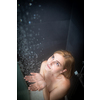 Pretty, young woman taking a long hot shower washing her hair in a modern design bathroom
