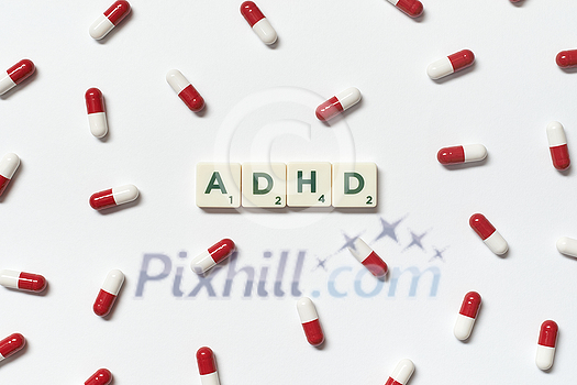 ADHD word formed of scrabble blocks and pharmaceutical pills strewn over white background. Attention deficit hyperactivity disorder and mental health awareness. ADHD word formed of scrabble blocks and pharmaceutical pills strewn over white background. Attention deficit hyperactivity disorder and mental health awareness.