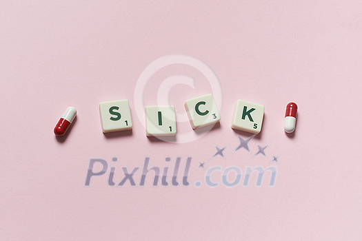 Sick word formed of scrabble blocks and pharmaceutical pills over pink background. Health and medical treatment concept. Sick word formed of scrabble blocks and pharmaceutical pills over pink background. Health and medical treatment concept.