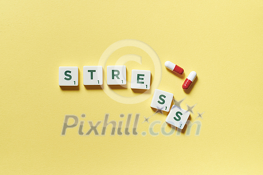 Stress word formed of scrabble tiles and pharmaceutical pills on yellow background. Mental health awareness. Stress word formed of scrabble tiles and pharmaceutical pills on yellow background. Mental health awareness.