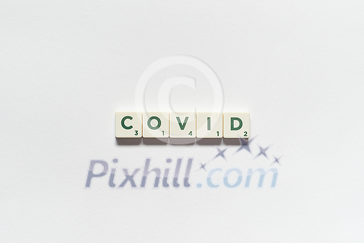 Covid word formed of scrabble blocks on white background. Coronavirus infection and medical treatment concept. Covid word formed of scrabble blocks on white background. Coronavirus infection and medical treatment concept.