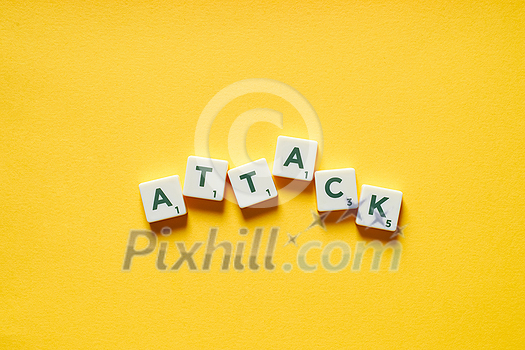 Attack word formed of messy scrabble tiles on yellow backdrop. Safety and health concept. Attack word formed of messy scrabble tiles on yellow backdrop. Safety and health concept.
