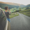 Traveling in nature, woman photographing alpine landscape with her smartphone
