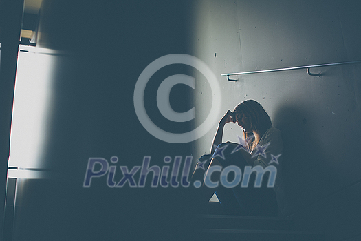 Depressed young woman sitting in a staircase, jobloss due to coronavirus pandemic, Covid-19 outbreak. Unemployment, economic crisis, financial distress concept Depressed young woman sitting in a staircase, jobloss due to coronavirus pandemic, Covid-19 outbreak. Unemployment, economic crisis, financial distress concept