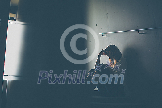 Depressed young woman sitting in a staircase, jobloss due to coronavirus pandemic, Covid-19 outbreak. Unemployment, economic crisis, financial distress concept