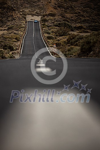 Long road in a mountain valley with a car on it - Teide National Park, Tenerife, Canary islands Long road in a mountain valley with a car on it - Teide National Park, Tenerife, Canary islands