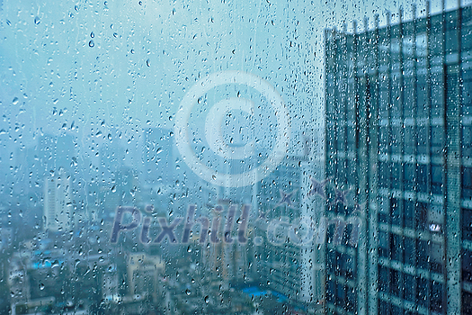 Rain water drops droplets on window glass texture with skyscrapers in background Rain water drops droplets on window glass texture with skyscrapers in background