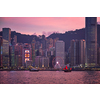 Tourist junk boat ferry with red sails and Hong Kong skyline cityscape downtown skyscrapers over Victoria Harbour in the evening. Hong Kong, China