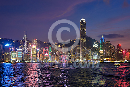 Hong Kong skyline cityscape downtown skyscrapers over Victoria Harbour in the evening illuminated with tourist boat ferries . Hong Kong, China Hong Kong skyline cityscape downtown skyscrapers over Victoria Harbour in the evening illuminated with tourist boat ferries . Hong Kong, China