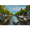 Amsterdam view - canal with tourist boat, bridge and old houses. Amsterdam, Netherlands