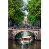 Amsterdam view - canal with boat passing under bridge and old houses. Amsterdam, Netherlands