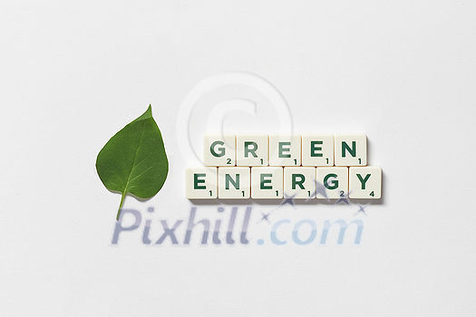 Green energy words formed of scrabble tiles with green tree leaf on white background. Nature and renewable energy concept. Green energy words formed of scrabble tiles with green tree leaf on white background. Nature and renewable energy concept.