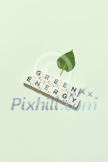 Green energy words formed of scrabble tiles with fresh tree leaf on light green background. Eco energy and natural resource conservation concept. Green energy words formed of scrabble tiles with fresh tree leaf on light green background. Eco energy and natural resource conservation concept.