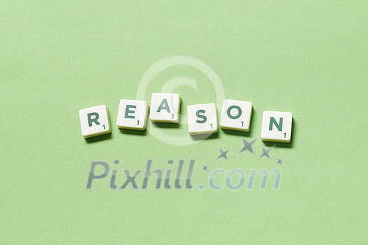 Reason word formed of scrabble tiles on green background. Creative business postcard idea in pastel palette. Reason word formed of scrabble tiles on green background. Creative business postcard idea in pastel palette.