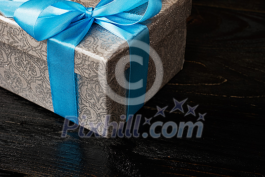 Gift birthday Christmas present concept - silver gift box with blue ribbon on dark wooden background Gift birthday Christmas present concept - silver gift box with blue ribbon on dark wooden background