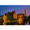 Famous view of Bruges tourist landmark attraction - Rozenhoedkaai canal with Belfry and old houses along canal with tree in the night. Brugge, Belgium