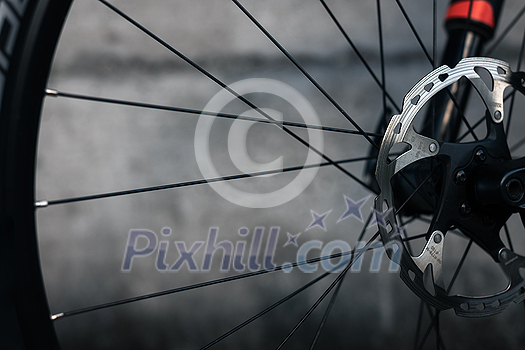 Hydraulic bicycle disk brakes, grey metal disc attached to bike wheel close up, effective popular mountain bicycle brakes. Hydraulic disk brakes on bicycle wheel, bicycle spokes gray background Hydraulic bicycle disk brakes, grey metal disc attached to bike wheel close up, effective popular mountain bicycle brakes. Hydraulic disk brakes on bicycle wheel, bicycle spokes gray background
